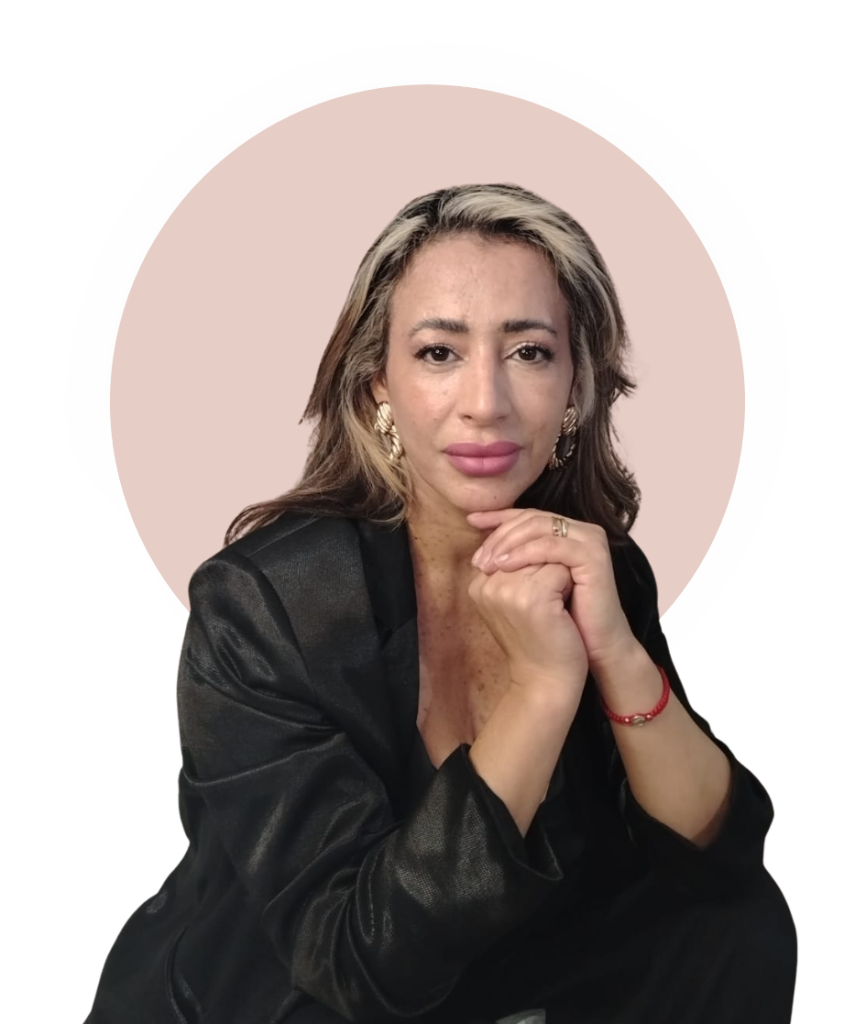 Retrato profesional de Nora Samudio con fondo rosa, vistiendo blazer negro y joyas doradas